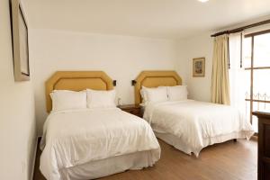 a bedroom with two beds with white sheets and a window at Pasaje Las Rosas in Cuernavaca