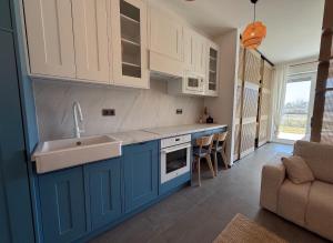 a kitchen with blue cabinets and a sink and a couch at The Balaton Nest! in Alsóörs +5 photos