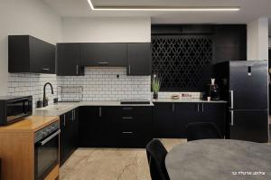 a kitchen with black cabinets and a table in it at וילת היוצר in Ya‘ara