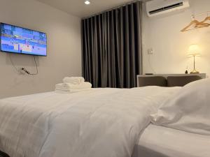 a bedroom with a white bed with a tv on the wall at ดิโอโซน THE Ozone in Ban Bung Sanan +8 photos