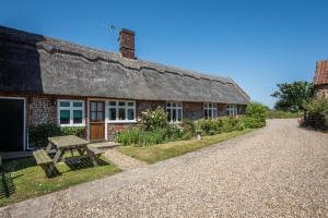a house with a thatched roof and a picnic table at 2 Bed in Bacton oc-710 in Bacton