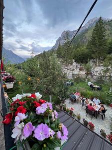a balcony with flowers and people sitting at tables at Guesthouse Demushi in Valbonë