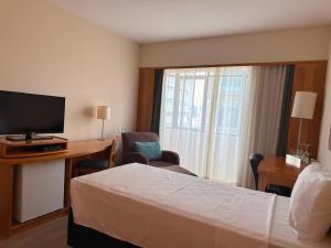 a hotel room with a bed and a desk and a television at Hotel & Residence Alphaville in Barueri