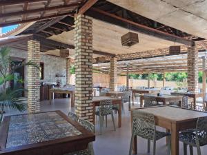 a restaurant with tables and chairs and a brick wall at Pousada Aruana in Canoa Quebrada