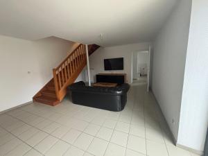 a living room with a black leather couch and a television at Gîtes de la Renaissance in Merlieux-et-Fouquerolles