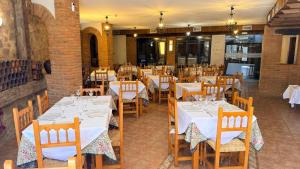 a restaurant with white tables and chairs in a room at Hotel Rural La Posada de Lía in Berzocana