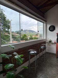 a room with two stools in front of a large window at Paraiso Mantiqueira in Paraisópolis