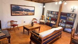 a living room with chairs and a table and bookshelves at Hotel Rural La Posada de Lía in Berzocana