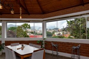 a table and chairs in a room with windows at Paraiso Mantiqueira in Paraisópolis