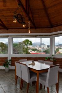 a dining room with a table and chairs and windows at Paraiso Mantiqueira in Paraisópolis +16 photos