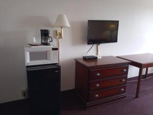 a hotel room with a microwave and a dresser with a tv at Hoosier Inn- Portland in Portland