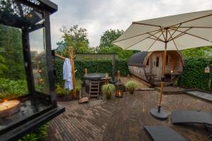 a patio with an umbrella and a grill at B&B Oud-Zilven Het Vogelhuisje in Loenen