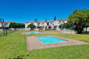 a swimming pool in a yard with a playground at Flamingo Park D1 Langebaan in Langebaan