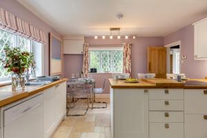 a kitchen with white cabinets and a table with flowers at 2 Bed in Woofferton oc-b29941 in Woofferton