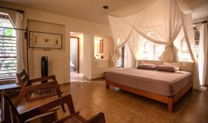 a bedroom with a bed in a room with windows at Villas Ecotucan in Bacalar
