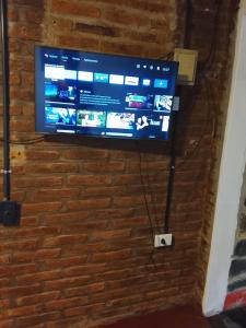 a flat screen tv hanging on a brick wall at alojamiento Villa sarita in Posadas