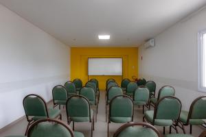 a conference room with green chairs and a whiteboard at Guarujá Vivah in Guarujá +62 photos