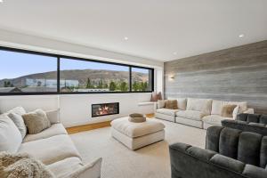 a living room with white furniture and a fireplace at Rubus St Residence by Sothebys Luxury Rental Homes in Wanaka