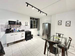 a kitchen with a table and a stainless steel refrigerator at Loft Studio Central in Nova Friburgo