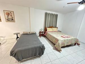 a bedroom with two beds and a table and a fan at Loft Studio Central in Nova Friburgo
