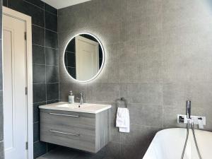 a bathroom with a sink and a mirror and a tub at Central Haven Dingle in Dingle +23 photos
