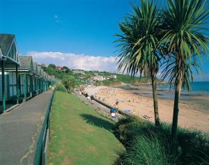 a beach with palm trees and people on the sand at 3 Bed in Mumbles oc-hh19 in The Mumbles