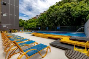 a pool with yellow and blue chairs and a swimming pool at Guarujá Vivah in Guarujá