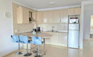 a kitchen with a table and blue chairs in it at LANI house - stunning pool in Palm-Mar