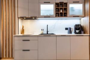 a kitchen with white cabinets and a sink at Czerwone Wierchy Premium Apartment in Zakopane