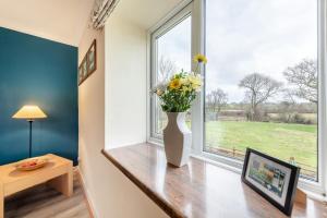 a vase of flowers sitting on a table in front of a window at 1 Bed in Drefach oc-m30848 in Llanwenog