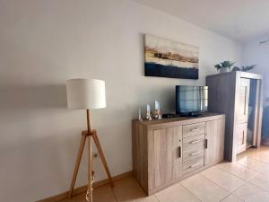 a room with a lamp and a dresser with a television at LANI house - stunning pool in Palm-Mar