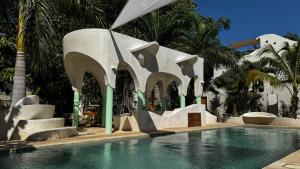 a swimming pool in front of a building with palm trees at Calle Ouvert in Mérida