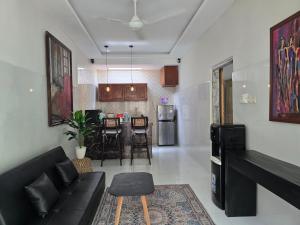 a living room with a black couch and a kitchen at Rumah Risa in Tanah Lot