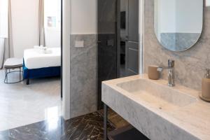 a bathroom with a large sink and a bedroom at Marmori Suites Cagliari in Cagliari