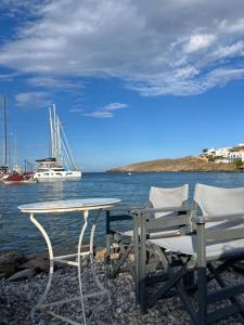 a table and two chairs sitting next to the water at Οικία Χωρας Κυθνου in Kithnos