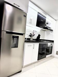 a stainless steel refrigerator in a kitchen with white cabinets at Apartamento Premier in Ibagué
