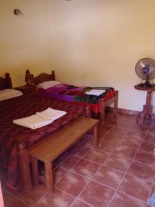 a room with two beds and a bench and a fan at MiskyPacha in Purmamarca