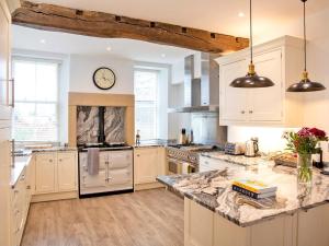 a kitchen with white cabinets and a clock on the wall at 7 Bed in Buxton oc-93808 in Tideswell