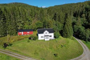 a white house on a hill with a red barn at Hundevennlig feriehus ved sjøen på Geisnes in Sørmoen +7 photos