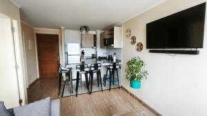a kitchen with a bar with stools and a tv on a wall at Departamento centro Temuco in Temuco