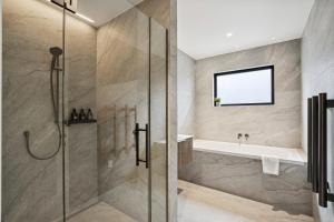 a bathroom with a shower and a tub at Rubus St Residence by Sothebys Luxury Rental Homes in Wanaka +14 photos
