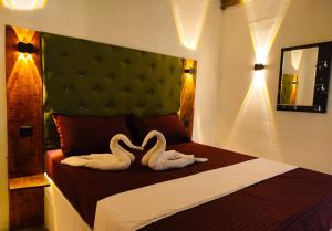 two swans sitting on a bed in a bedroom at Cocos cabana in Ilandaiyadi