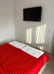 a bed with a red blanket and a flat screen tv at Apartament Karim in Drobeta-Turnu Severin