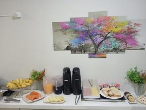 a table with plates of food and a tree on the wall at Ribeiro Flat in Araxá +32 photos
