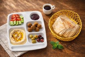 a tray with a plate of food and a basket of fruit at Friends Oasis in Aqaba