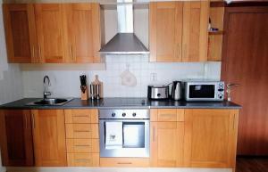a kitchen with wooden cabinets and a stove and a microwave at Mountain View Apartment Bansko in Bansko