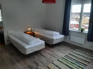 a room with two beds and a table and a window at Nära lasarettet i Lindesberg in Lindesberg