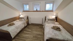 two twin beds in a room with two windows at Apartmán Altis in Tatranska Strba