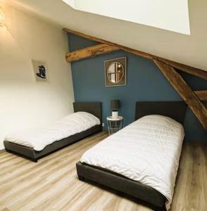 a room with two beds and a blue wall at Le chai de Peyssard, piscine chauffée. in Château-lʼÉvêque