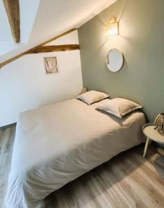a bedroom with a large white bed and a table at Le chai de Peyssard, piscine chauffée. in Château-lʼÉvêque